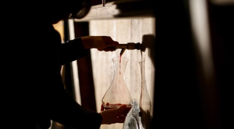 person filling wine from a barrel