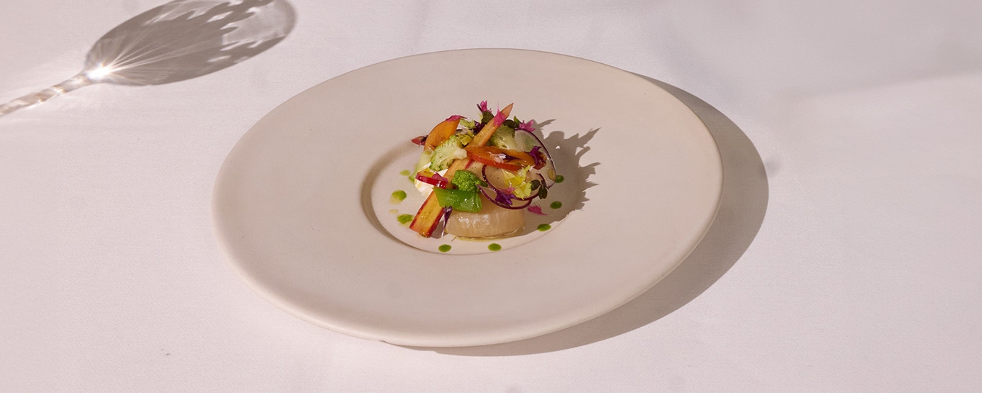 Salad dish on a white table with a shadow of a wine glass