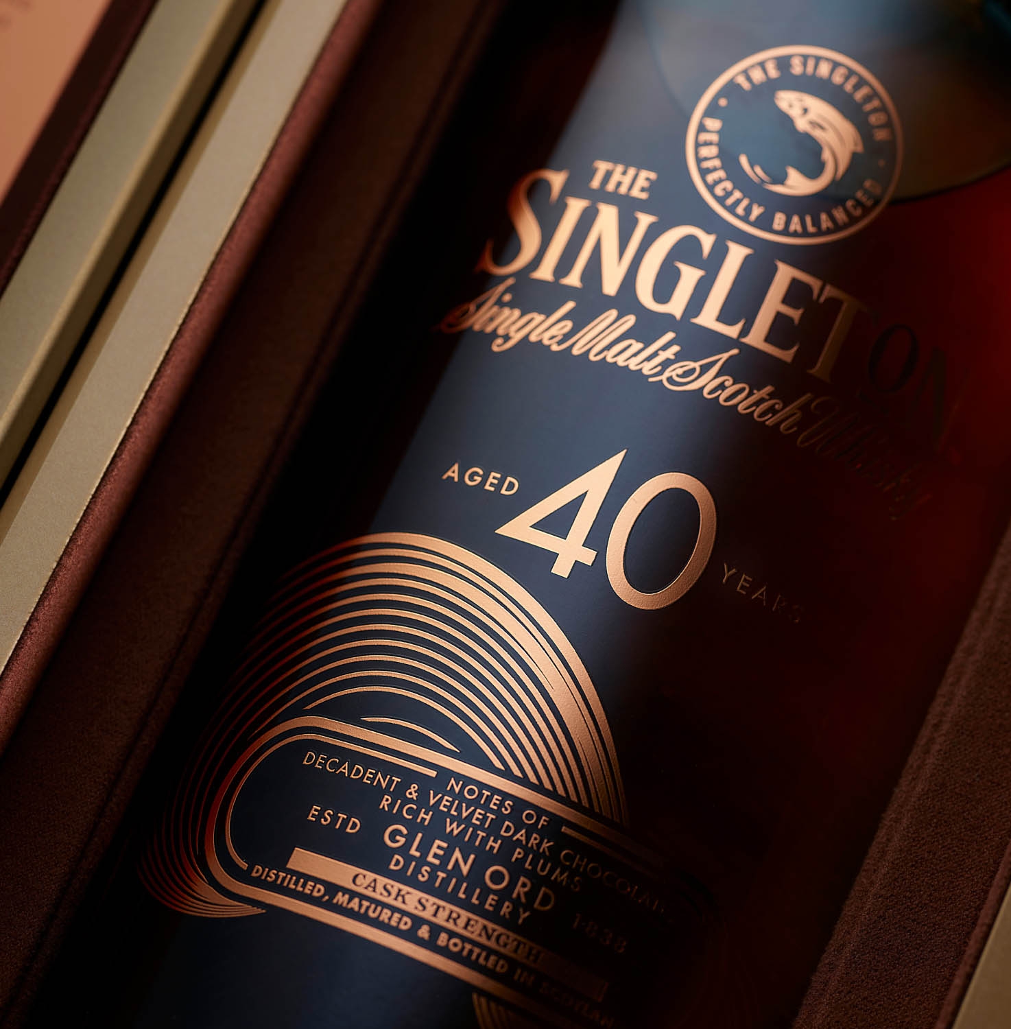 singleton whisky bottle next to packaging on a textured brown background