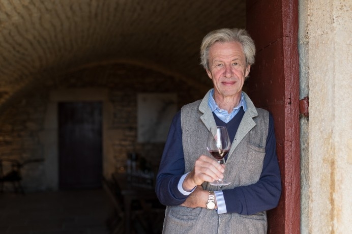 older gentleman leaning agains door frame with red wine in hand