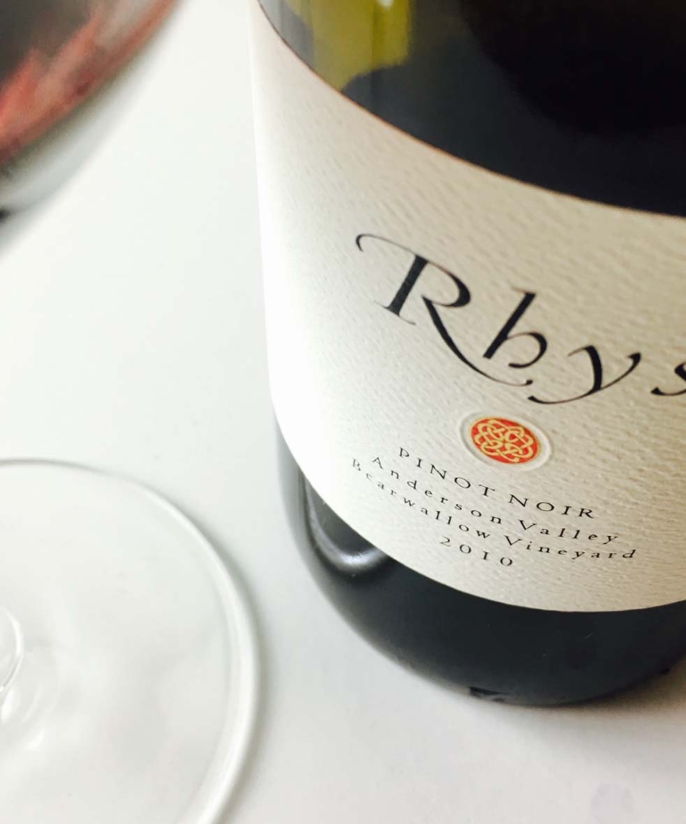 close up bottle of wine with white label that says Rhys