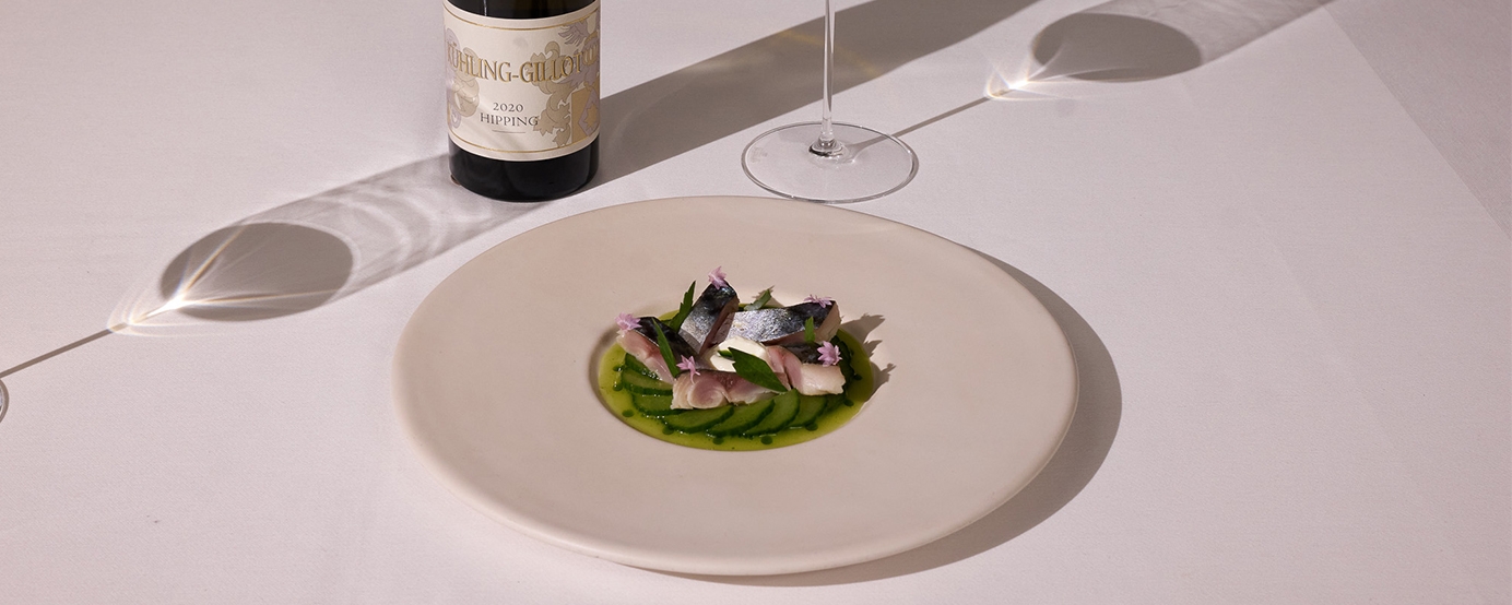 Fish dish on a plate beside a two wine glasses