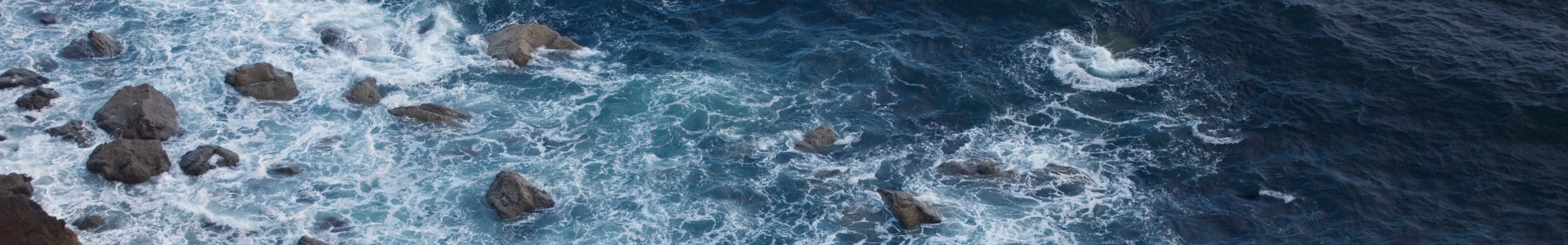 Aerial shot of waves crashing into rocks