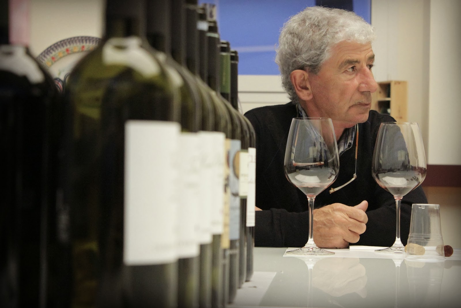 Close up of bottles with man drinking wine in back