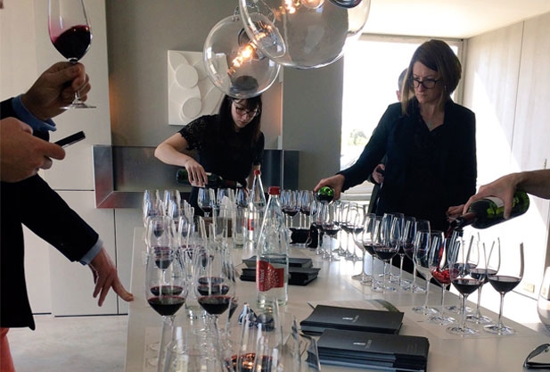 A table full of glasses with people pouring themselves glasses of wine