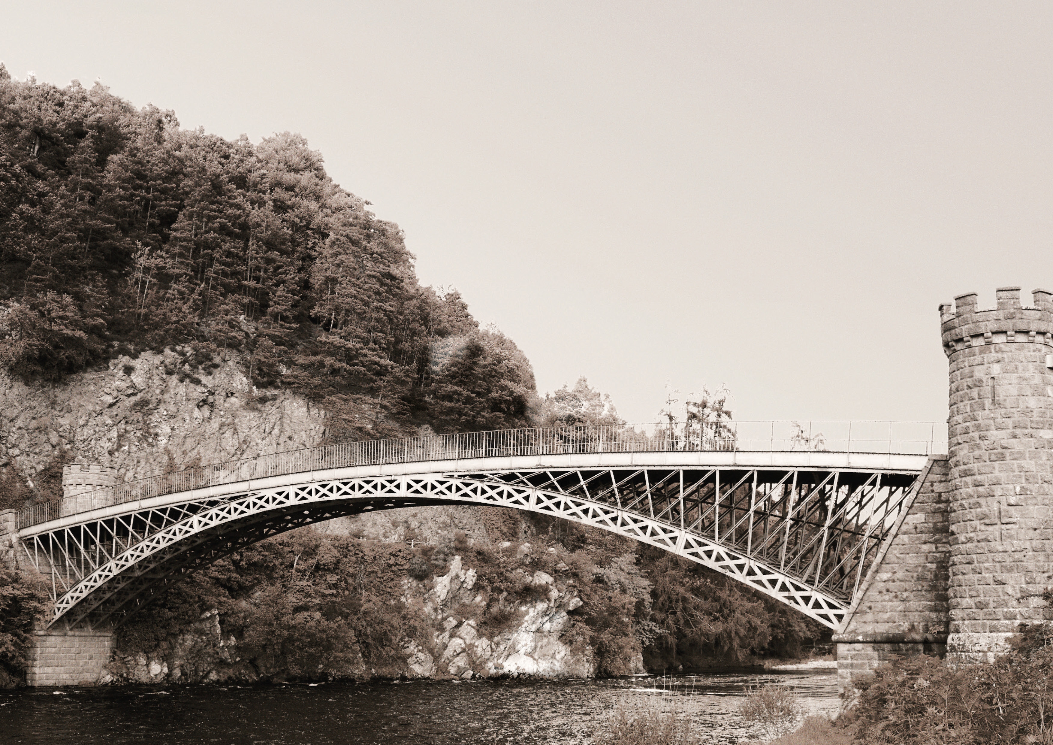 bridge over a river with a tower on one side and a tree on the other