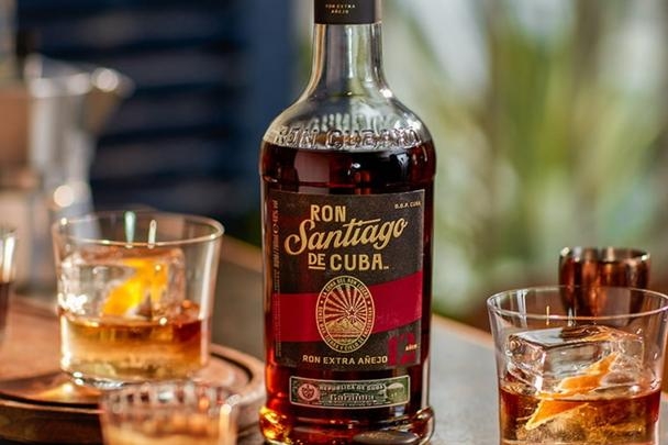 Bottle next to a glasses of rum with ice and orange