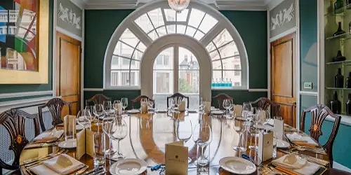A long dining table, set for eating, in front of an arch window