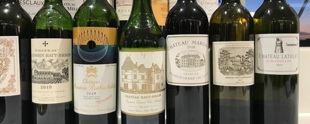 A row of seven wine bottles from Bordeaux 2019