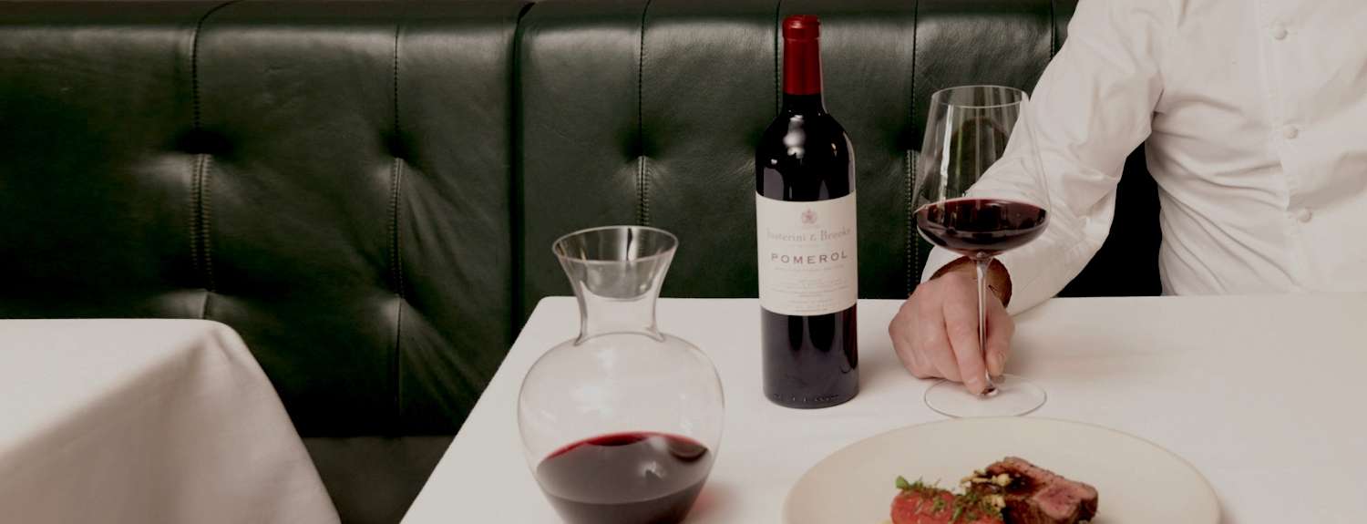 Man having dinner in a restaurant with a glass and bottle of justerinis red wine