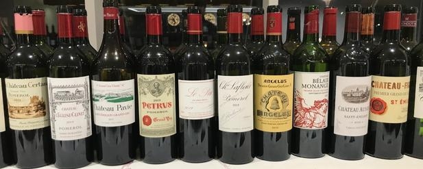 A row of twelve red wine bottles from Bordeaux 2019
