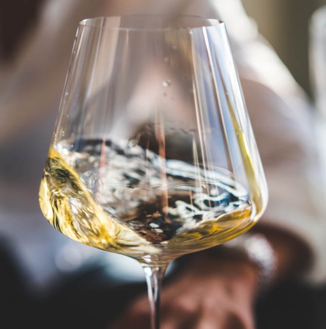 close up of wine glass with white wine swishing in the glass